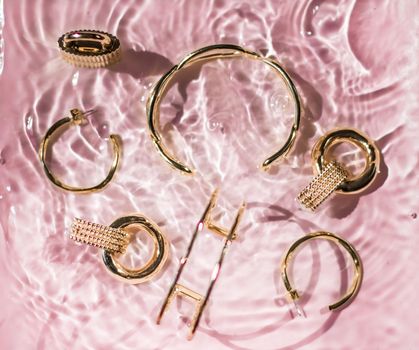 Jewellery branding, fashion gift and luxe shopping concept - Golden bracelets, earrings, rings, jewelery on pink water background, luxury glamour and holiday beauty design for jewelry brand ads