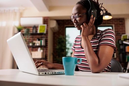 Smiling woman in headphones watching tv series online on laptop, freelancer having break from work. Streaming service, home entertainment, pastime leisure activity concept