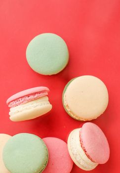 Pastry, bakery and branding concept - French macaroons on fruity red background, parisian chic cafe dessert, sweet food and cake macaron for luxury confectionery brand, holiday backdrop design