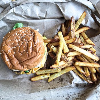 A sandwich sitting on top of a pile of fries. High quality photo