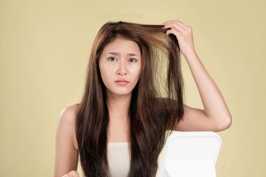 Ardent young girl feels insecure about her damaged hair. Beauty concept of brittle hair and how to treat it.