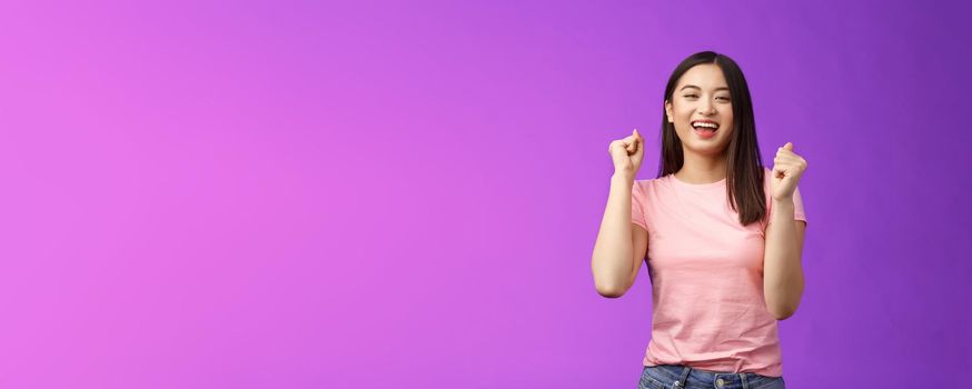 Hooray lucky win. Cheerful attractive astian girl make fist pump, dancing celebrate victory, stand purple background joyful, achieve excellent news grinning happily, move rhythm music.