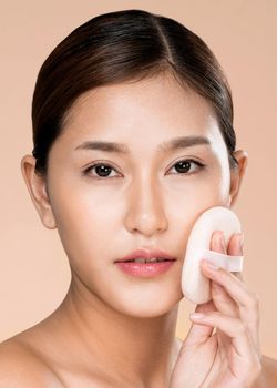 Closeup ardent woman applying her cheek with dry powder and looking at camera. Portrait of younger with perfect makeup and healthy skin concept.