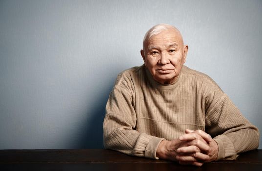 Pensive and thoughtful senior man sitting at the table