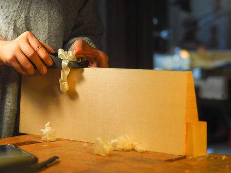 Close up of professional master artisan luthier painstaking detailed work on wood violin in a workshop.