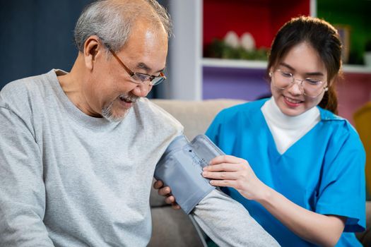 Asian nurse visit patient senior man at home she measuring arterial blood pressure on arm in living room, Doctor woman examine do checking old man client heart rate with pulsimeter monitor, Healthcare