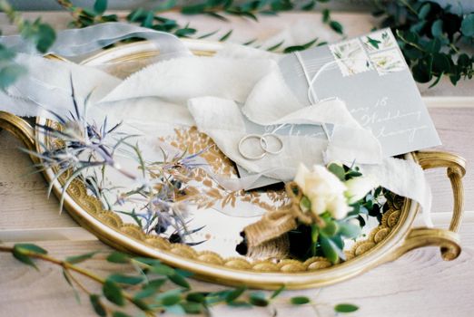 Wedding rings lie on an envelope on a golden tray. High quality photo