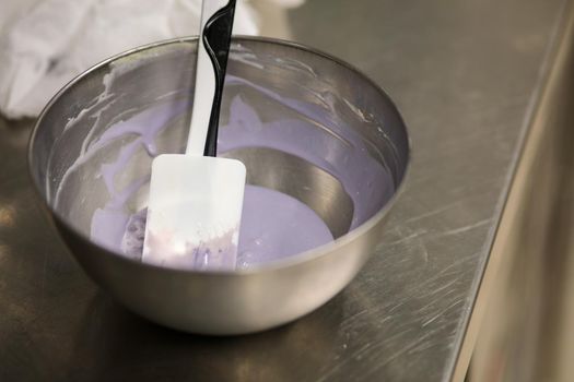 chef making for icing a lilac drip cake in the professional kitchen lab