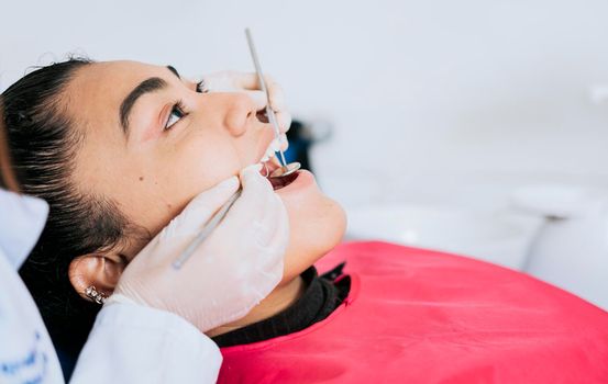 Close up of professional dentist cleaning female patient teeth, Close up of a dental specialist cleaning a patient's teeth. Side view of dentist cleaning female patient teeth with copy space