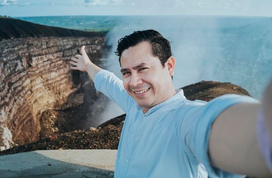 Tourist taking a selfie at a viewpoint. Handsome tourist taking a selfie on vacation. Adventurous man taking a selfie at a viewpoint. Close up of person taking an adventure selfie