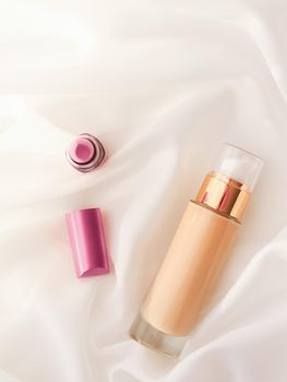 Cosmetic branding, glamour and skincare concept - Beige tonal cream bottle make-up fluid foundation base and pink lipstick on silk background, cosmetics products as luxury beauty brand holiday design