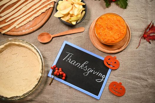 View from above of fresh raw ingredients for making a homemade American classic apple pie with pumpkin. Black board with the inscription - Thanksgiving Day . Autumn holidays. Still life with food