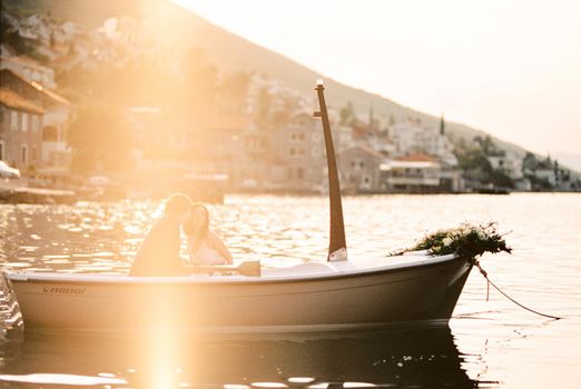 Man and woman are sitting in a boat with oars moored near the shore. High quality photo