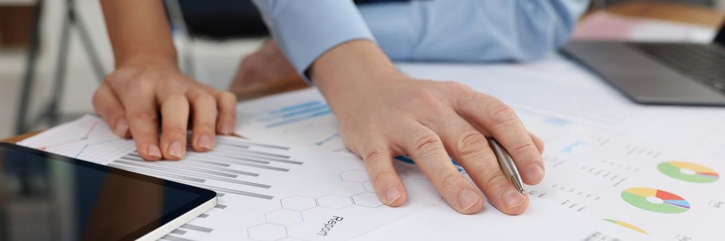 Close-up of coworkers prepare annual report together, end of year, chaos in corporation. Business papers with graphs on desk. Business, economy concept