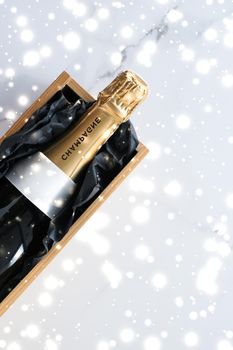 New Years Eve, happy holidays and luxury present concept - Christmas holiday champagne bottle and a gift box and shiny snow on marble background