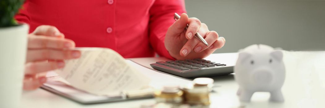 Close-up of accountant count on black calculator, cash coin on office workplace. Calculation of income, tax expenses, piggy bank. Business, finance concept