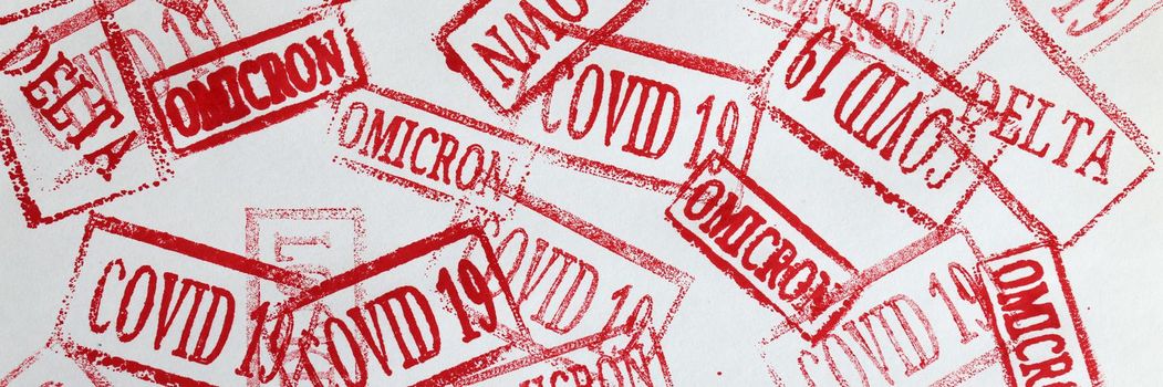 Red ink stamps covid19 and omicron delta lockdown closeup background. Global pandemic coronavirus infection concept