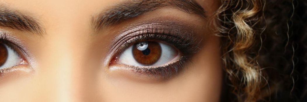 Close-up of latino american beautiful woman with brown eyes, curly hairstyle posing for picture. Attractive lady with exotic appearance. Modeling concept