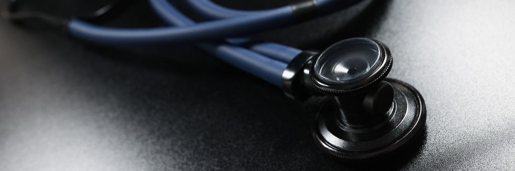 Close-up of doctor stethoscope equipment on dark surface, tool for patient diagnostic. Instrument to listen heartbeat and breath. Medicine, health concept