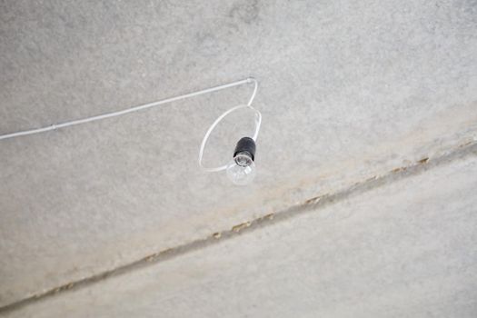 Light bulb on the ceiling. Lonely light bulb and wire sticking out of the ceiling during a repair