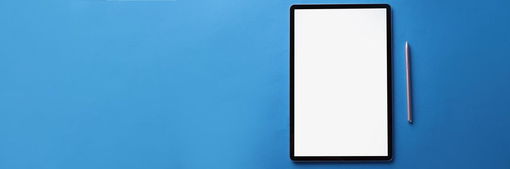 Top view of set of black screen modern tablet device with reflection and silver pen on blue surface, turnoff gadget. Technology, mockup concept. Copy space