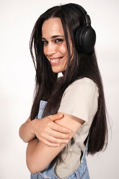 A young casual dressed female musician looking at camera listening to some music with headphones