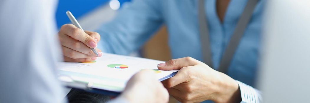 Close-up of female worker make correction on business paper with pen. Lady in suit express idea to colleague. Business, plan, creative, strategy concept