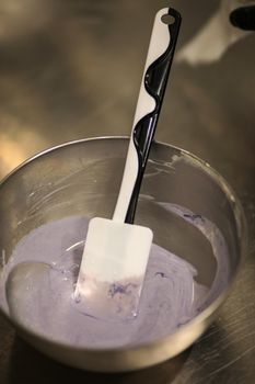 chef making for icing a lilac drip cake in the professional kitchen lab