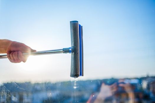Window cleaning in high-rise buildings, houses with a brush. Window cleaning brush. Large window in a multi-storey building, cleaning service. Dust removal and glass washing.