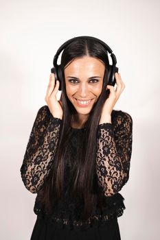 A young elegant female musician looking at camera listening to some music with headphones