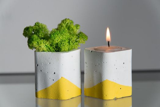 candles and moss in white and yellow concrete candle holders.