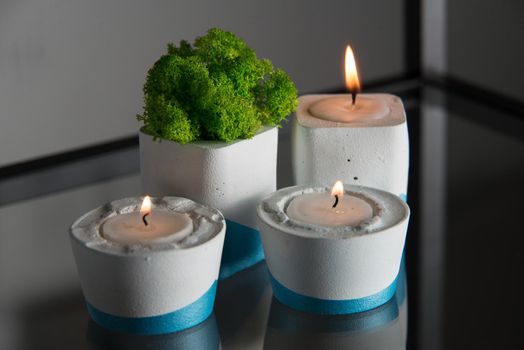 candles and moss in white and blue concrete candle holders.