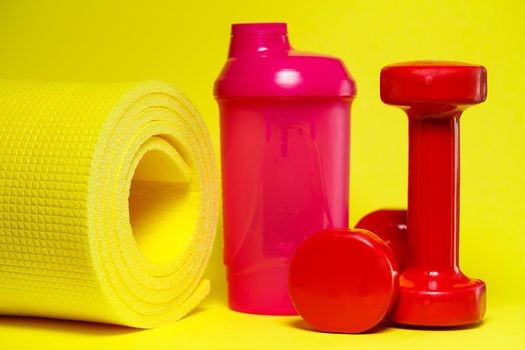 red dumbbells, pink shaker, yellow mat, colored background, sports, energy drink, gym equipment