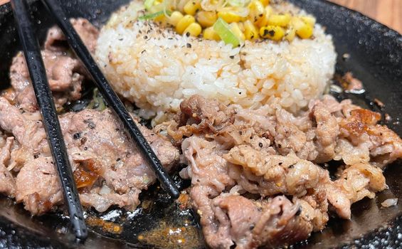 selective focus grilled beef steak with korean sauce bulgogi on top of rice with slice of pepper and sweet corn - korean and japanese food style in a restaurant