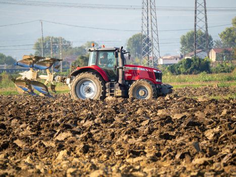 4k video of red tractor plowing the land in the countryside.