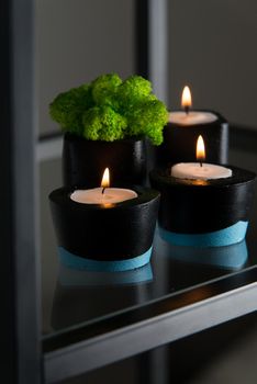 Candles and moss in black and blue concrete candle holders.