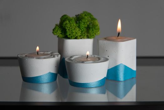 candles and moss in white and blue concrete candle holders.