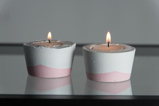 Two candles in white and pink concrete candle holders.