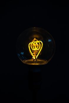 A classic Edison light bulb on black background with space for text. Illuminated light bulb on black background