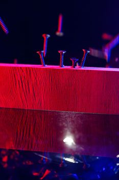 Screws screwed into a wooden beam in hard red light