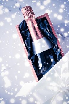 Celebration, drinks and branding concept - Champagne bottle and gift box on blue holiday glitter, New Years, Christmas, Valentines Day, winter present and luxury product packaging for beverage brand