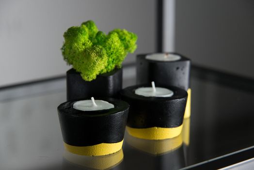 candles and moss in black and yellow concrete candle holders.