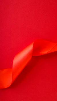 Branding, holidays and luxe brands concept - Abstract curly silk ribbon on red background, exclusive luxury brand design for holiday sale product promotion and glamour art invitation card backdrop