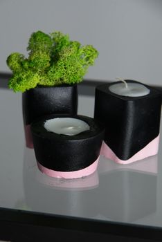 candles and moss in black and pink concrete candle holders.