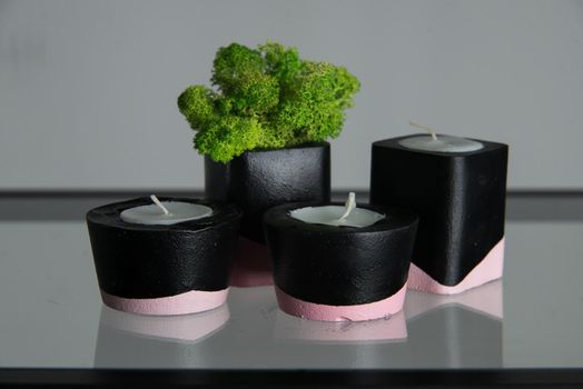 candles and moss in black and pink concrete candle holders.