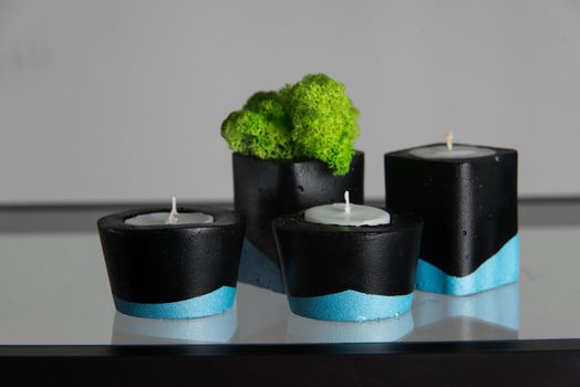 Candles and moss in black and blue concrete candle holders.