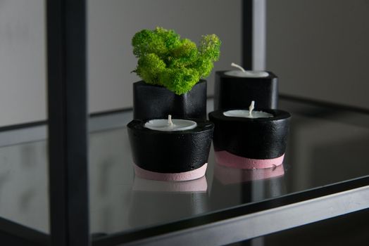 candles and moss in black and pink concrete candle holders.