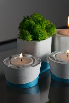 candles and moss in white and blue concrete candle holders.