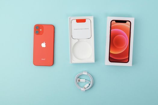 Tyumen, Russia-July 18, 2022: iPhone 12 mini Product red with retail box. Top view, blue background
