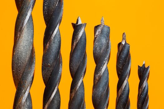Drills for wood of different sizes for a drill on an orange background. Construction tool